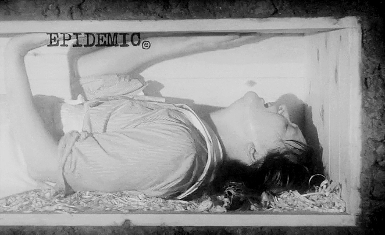 Cross-section of a simple wooden coffin buried underground, the woman inside gasping desperately for air and holding her hands up against the lid. 