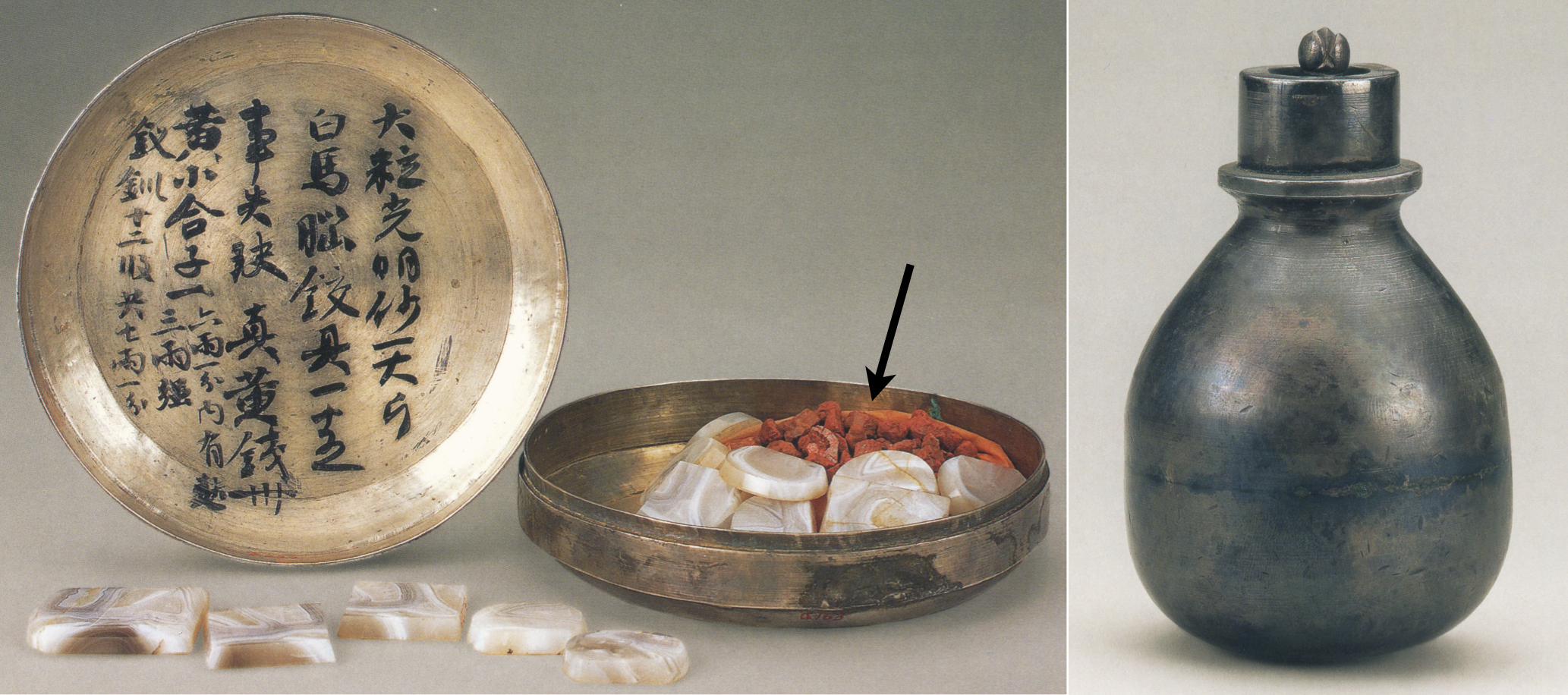 Two photographs of cinnabar and an alchemical utensil. On the left is a photograph of a round, shallow, silver box containing a dozen pieces of red cinnabar (indicated by an arrow) and a dozen small pieces of flat, tile-shaped, white agate both inside and outside the box. On the lid of the box are Chinese characters describing the name and amount of the cinnabar and other items in the box. On the right is a picture of a pomegranate-shaped silver jar.