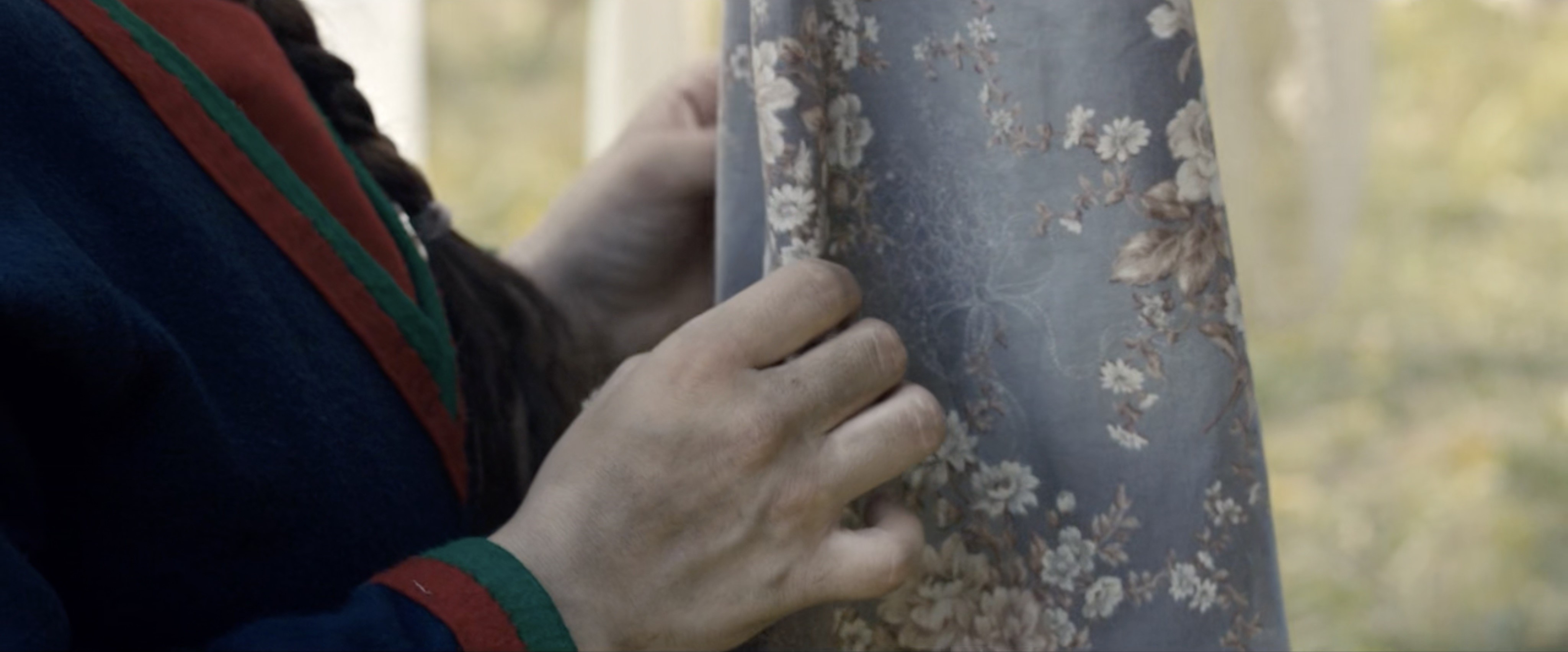 “Close-up photo of a torso and hand gently holding a flowered cloth.”