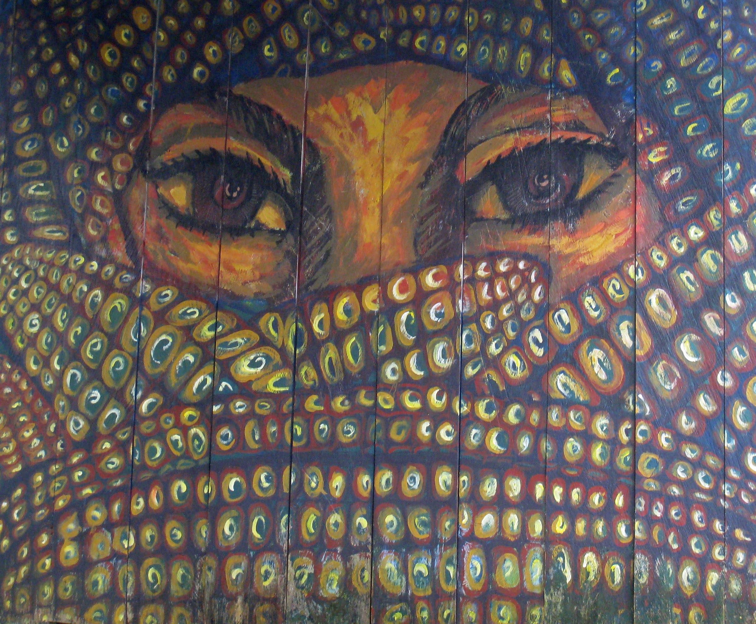 Close up of painted mural of woman's eyes surrounded by maize cobs.