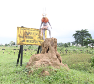A statue of a person in a garment standing on a mound of dirt

Description automatically generated