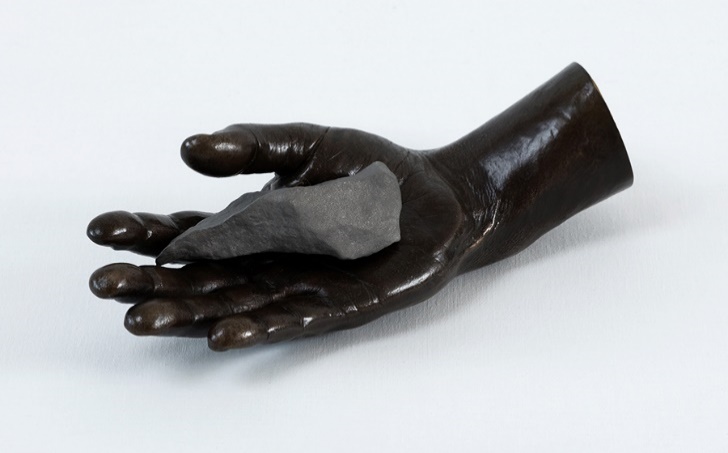 A black hand holding a rock

Description automatically generated