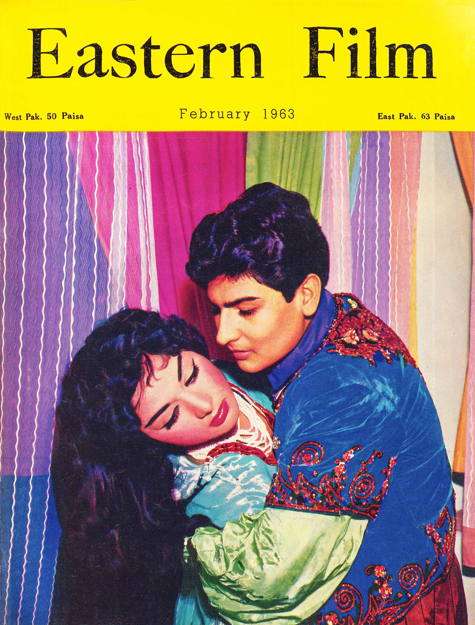 A magazine cover shows a young man dressed in an embroidered tunic embracing a woman with long cascading hair wearing a shiny dress and necklace.