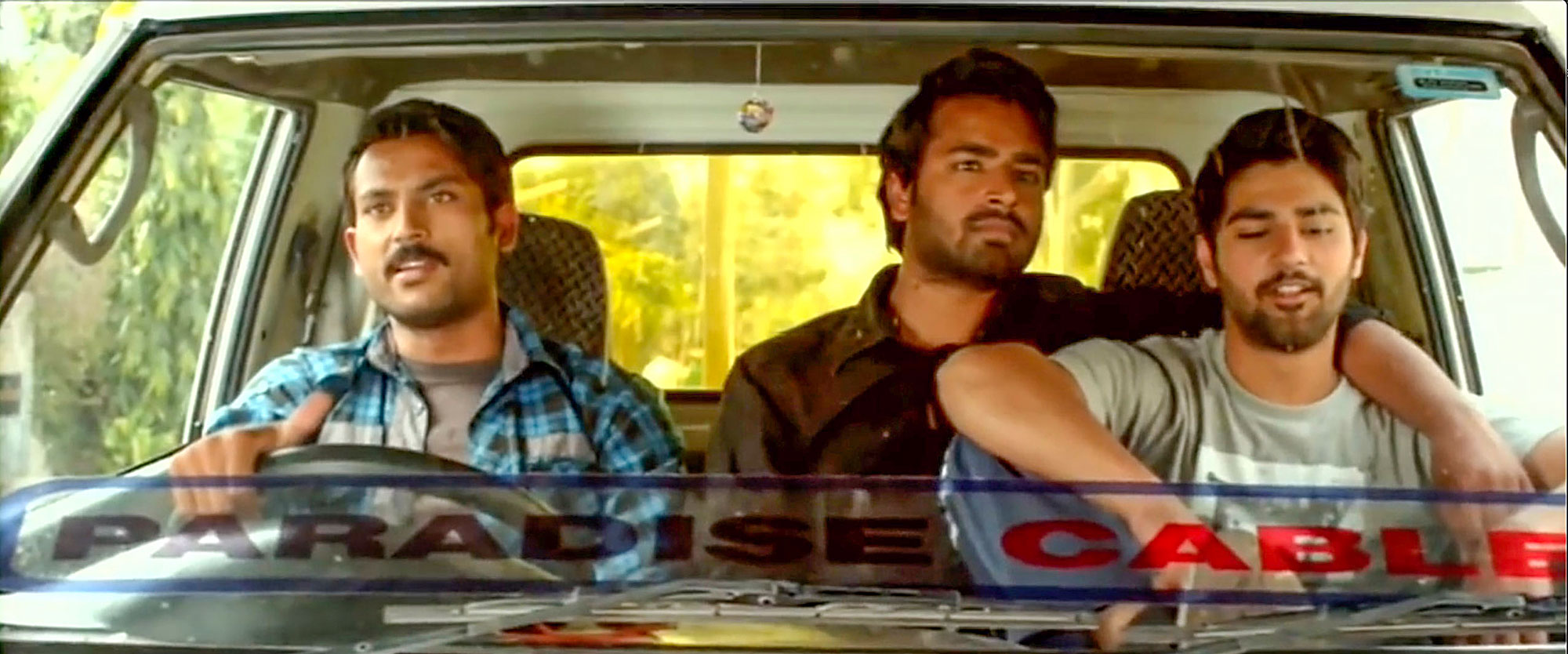 A shot looking in through a truck’s windshield, showing three casually dressed young men seated in the vehicle.