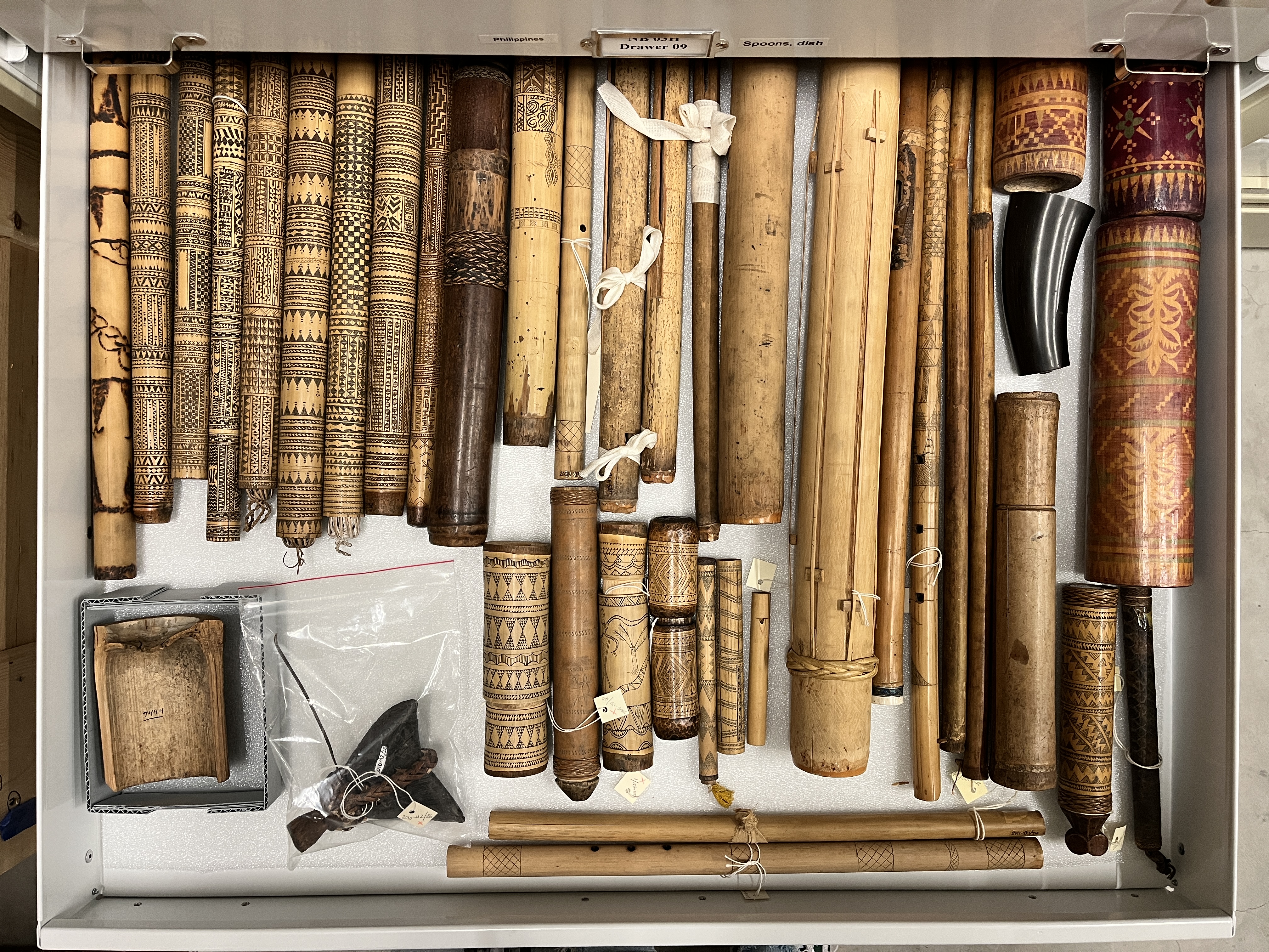 A drawer featuring a variety of instruments and water carriers made from bamboo and other woods from the Philippines.