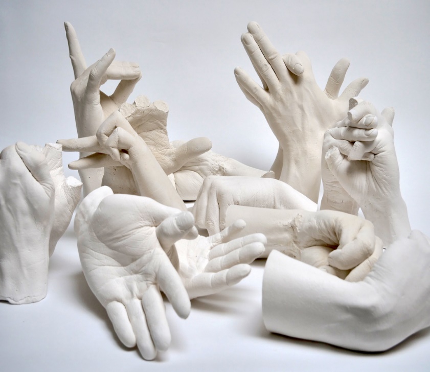 A group of hands in white plaster

Description automatically generated