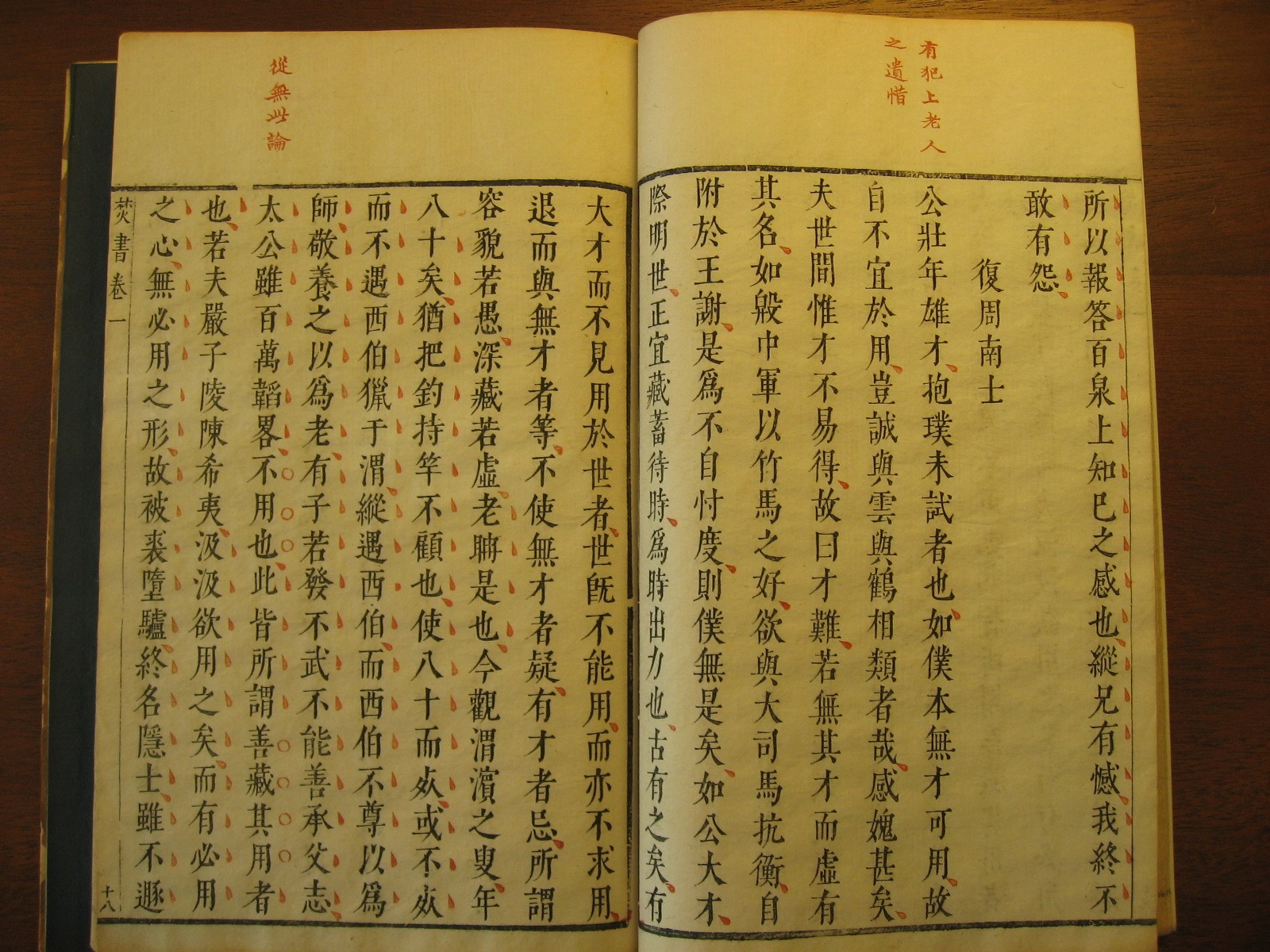 Two pages of an open book printed with black Chinese characters, with red marks besides most of the characters and a handful of red Chinese characters at the top of each page.