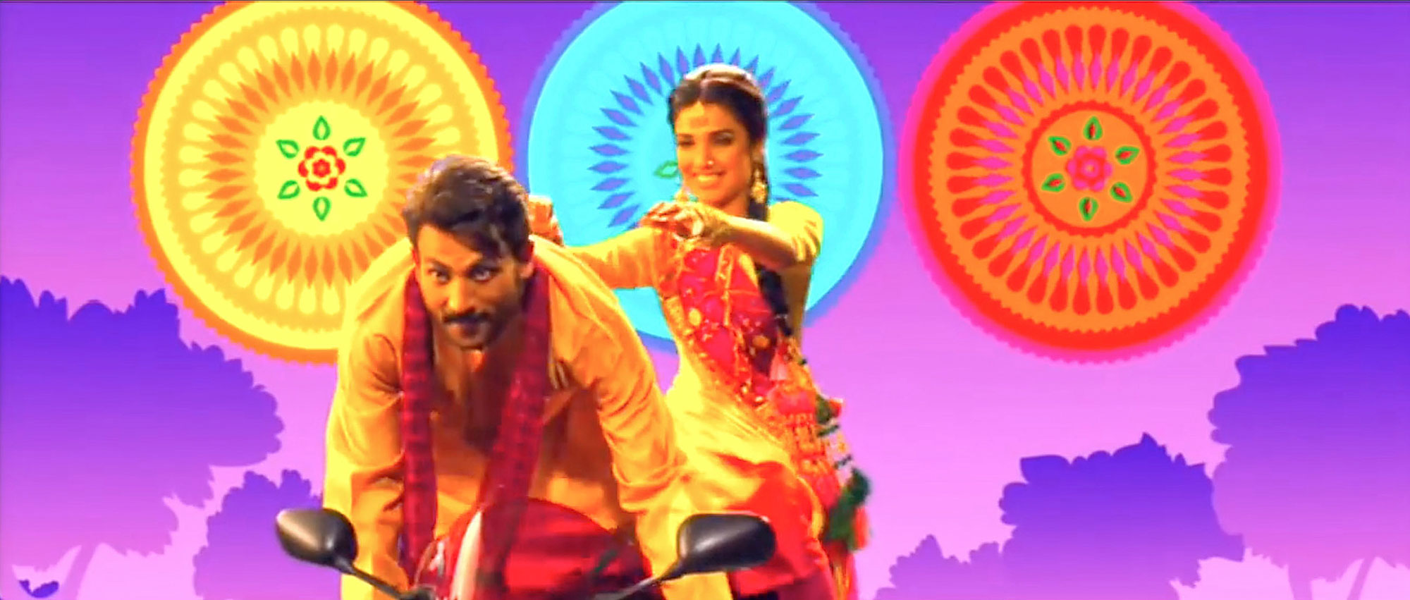 A young man wearing a scarf playfully rides a motorcycle while a woman seated behind him smiles and gestures him onwards. The background, composed of computer graphics, shows three large, round, ornamental forms in a row floating above rendered tree silhouettes.