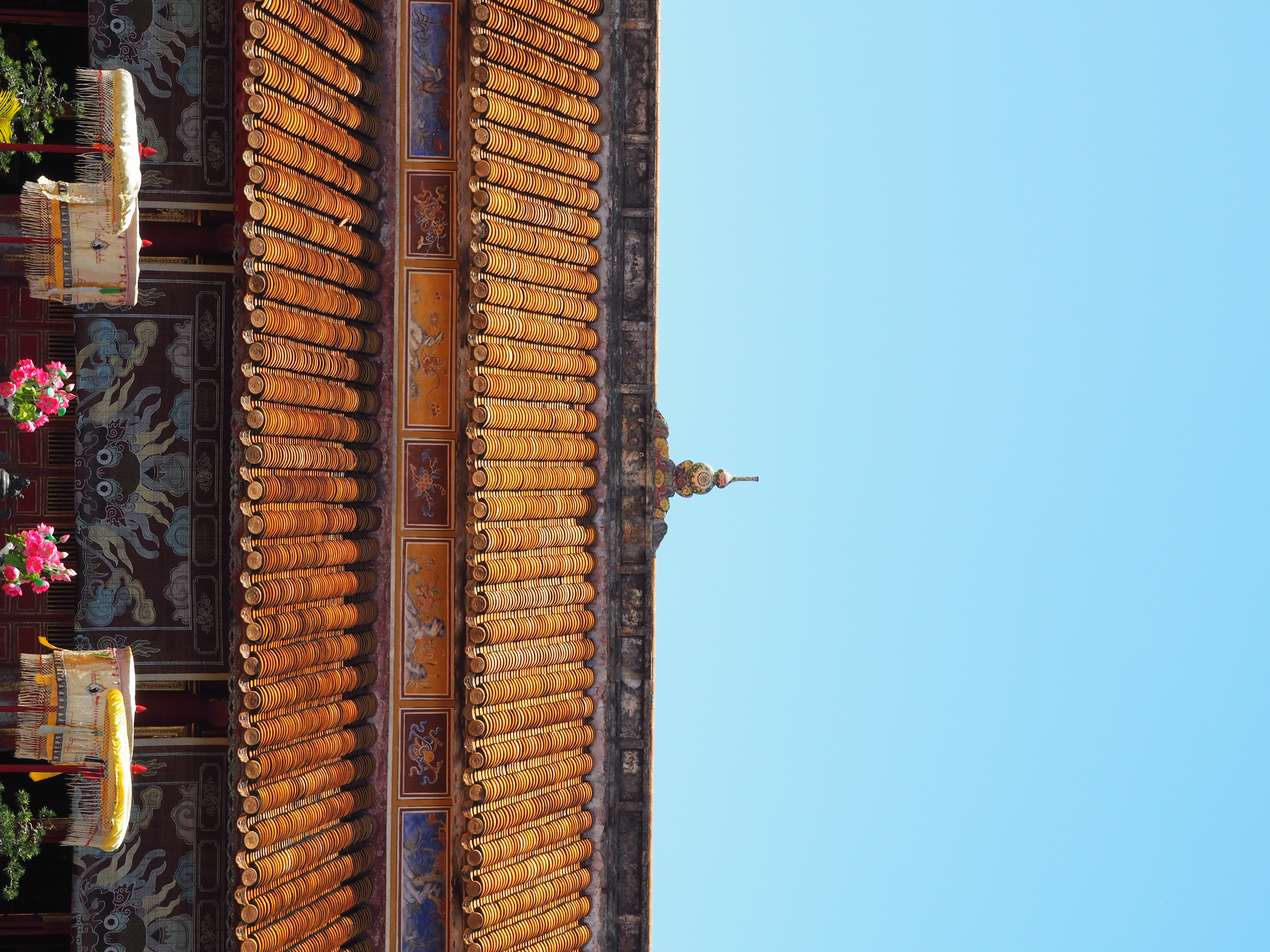 The two tiers of a golden-colored roof, with painted friezes and a squash-like ornament at the top.