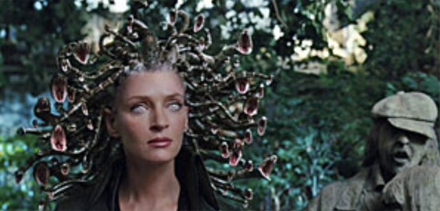 A pale woman, Medusa, with soft skin in a over grown greenhouse surrounded by statues of people as he eyes glow and the snakes on her head stare straight forward with fangs showing. 