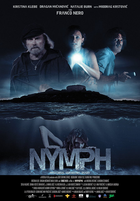 image is a poster of the film Mamula. On the top, three people (an old man, a young woman, and a young man) loom, ghostly, over a dark island. They are carrying flashlights and look terrified and disheveled. On the bottom, under the ocean line, a beautiful woman peers eerily over the title of the film in big stone letters, "Nymph." Color scheme is gray-black-dark blues.