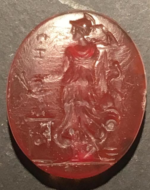 An oval shaped Intaglio (engravement onto in this case sard) depicting Cassandra kneeling at the image of Athena by her altar